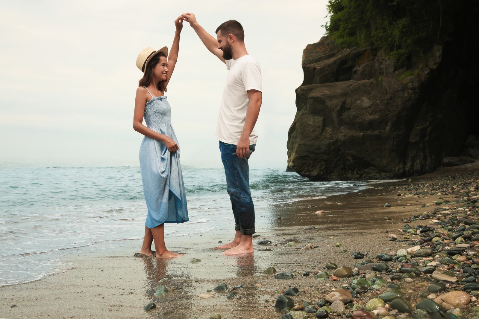 Photo of happy young couple dancing on beach near sea