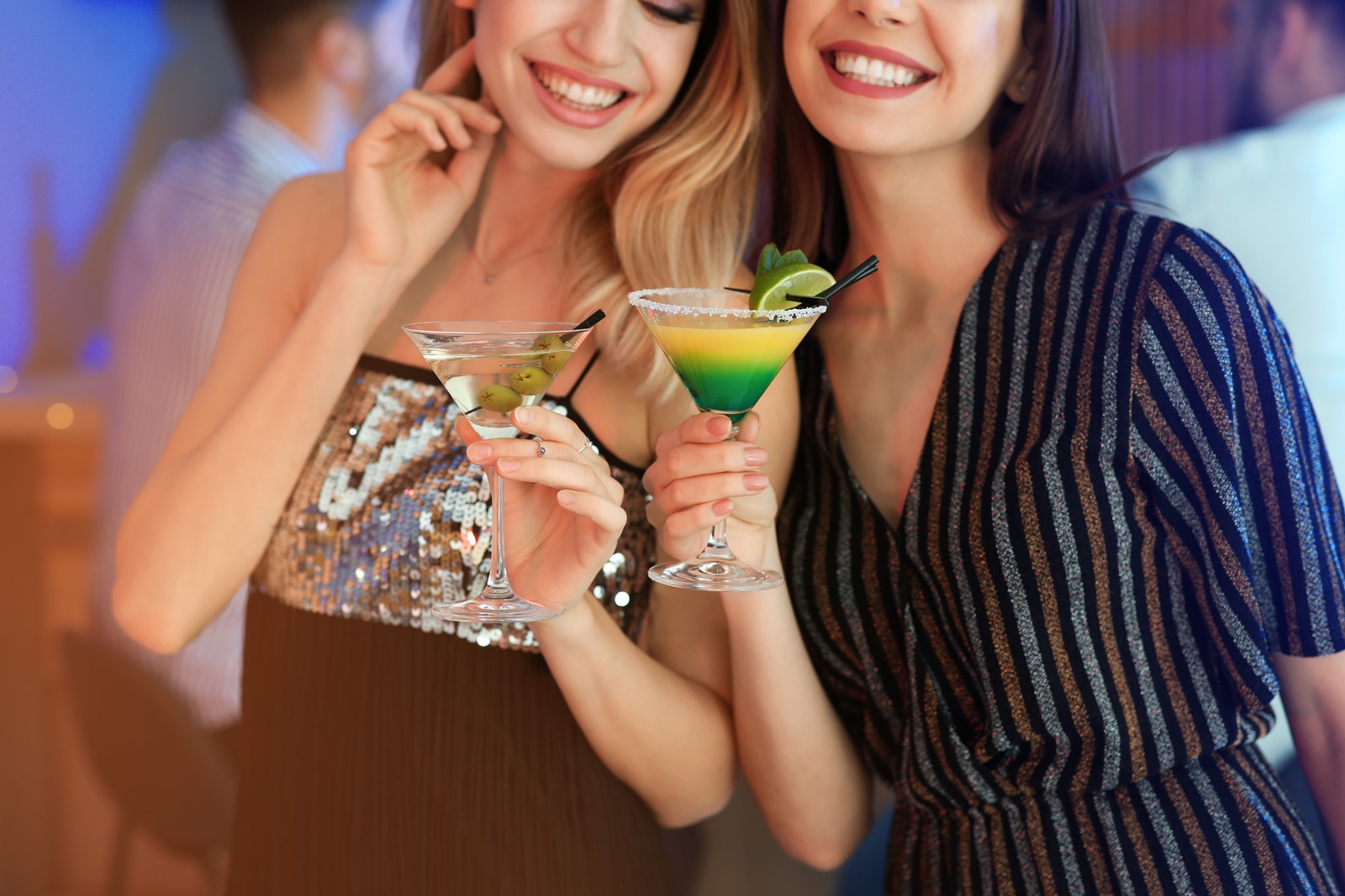 Photo of young women with martini cocktails in bar, closeup