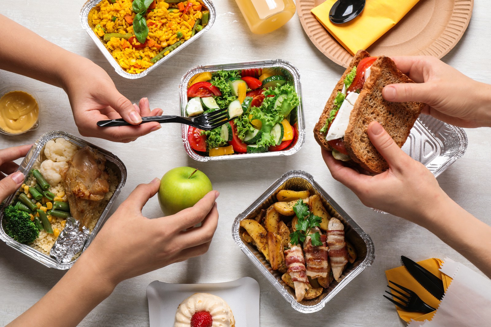 Photo of people with lunchboxes at white wooden table, top view. Healthy food delivery