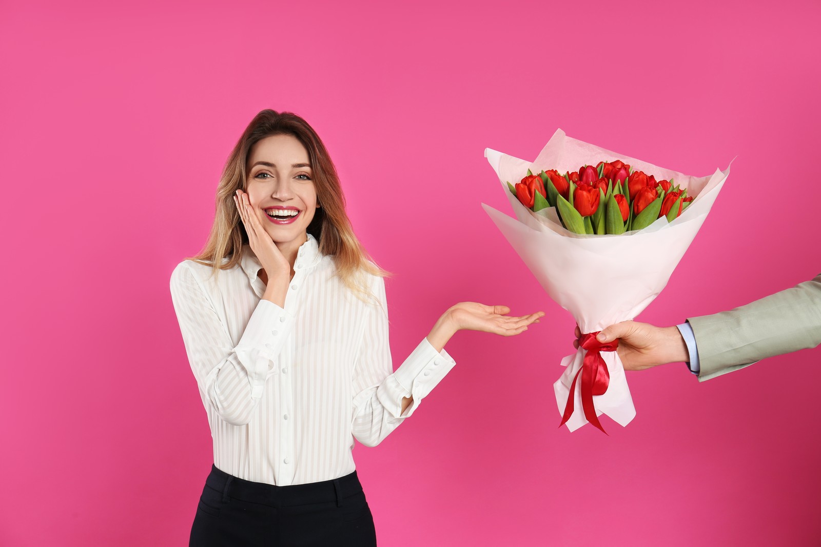 Photo of happy woman receiving red tulip bouquet from man on pink background