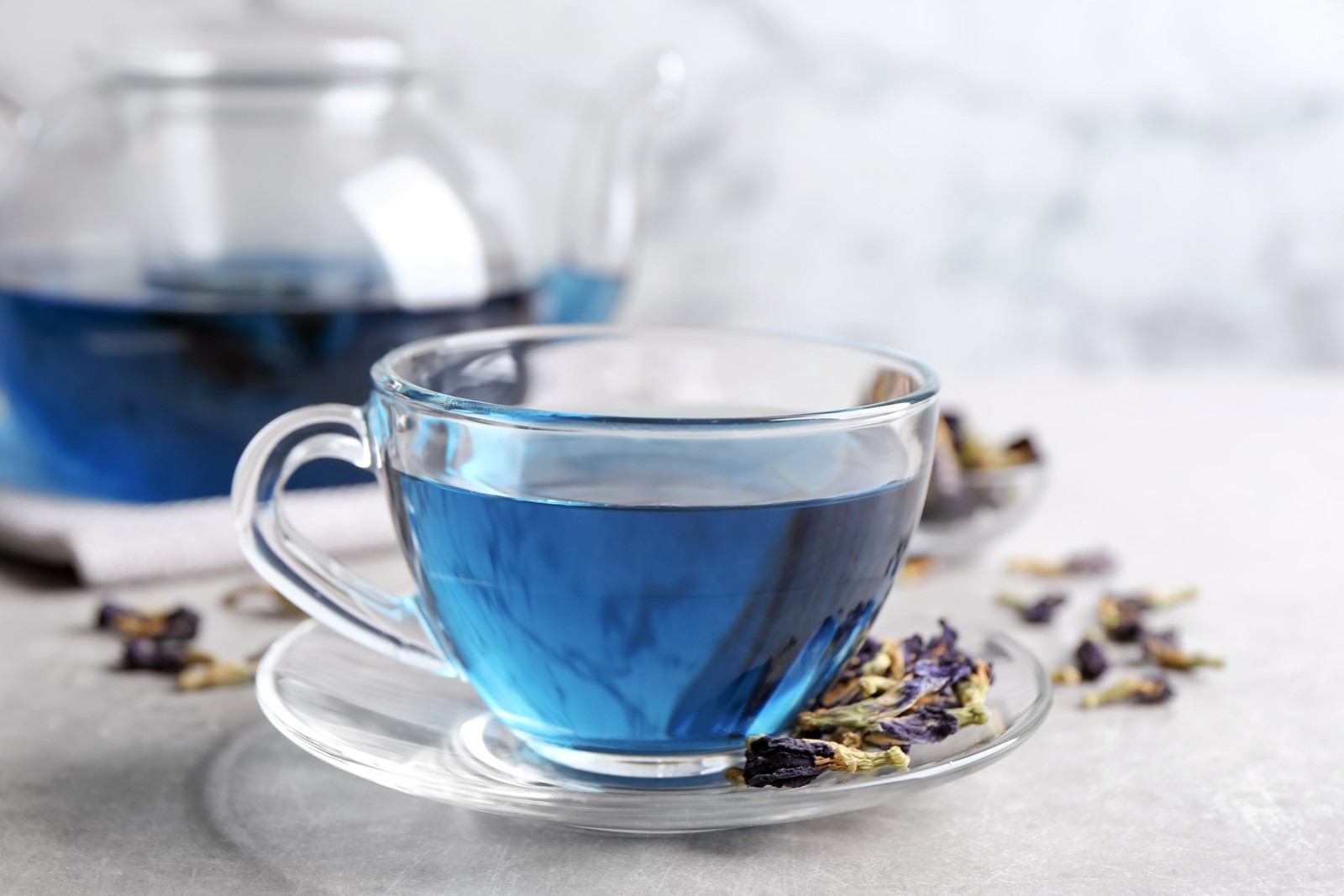 Photo of glass cup of organic blue Anchan on light table. Herbal tea