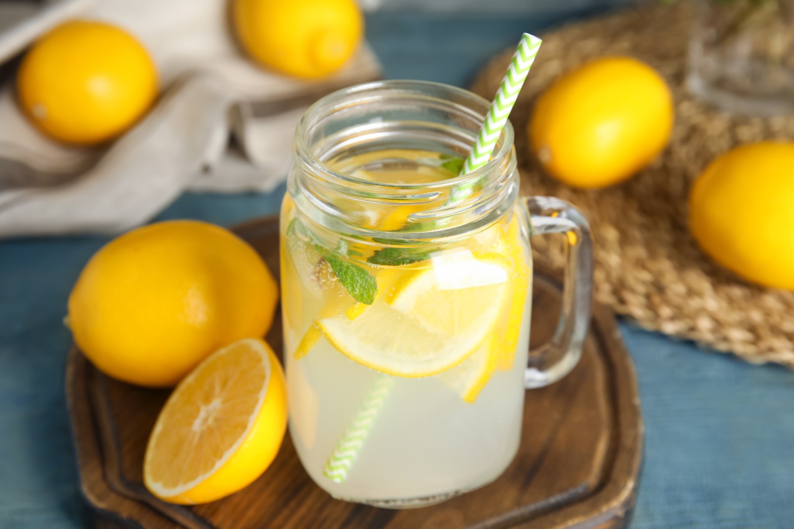 Photo of cool freshly made lemonade and fruits on light blue wooden table