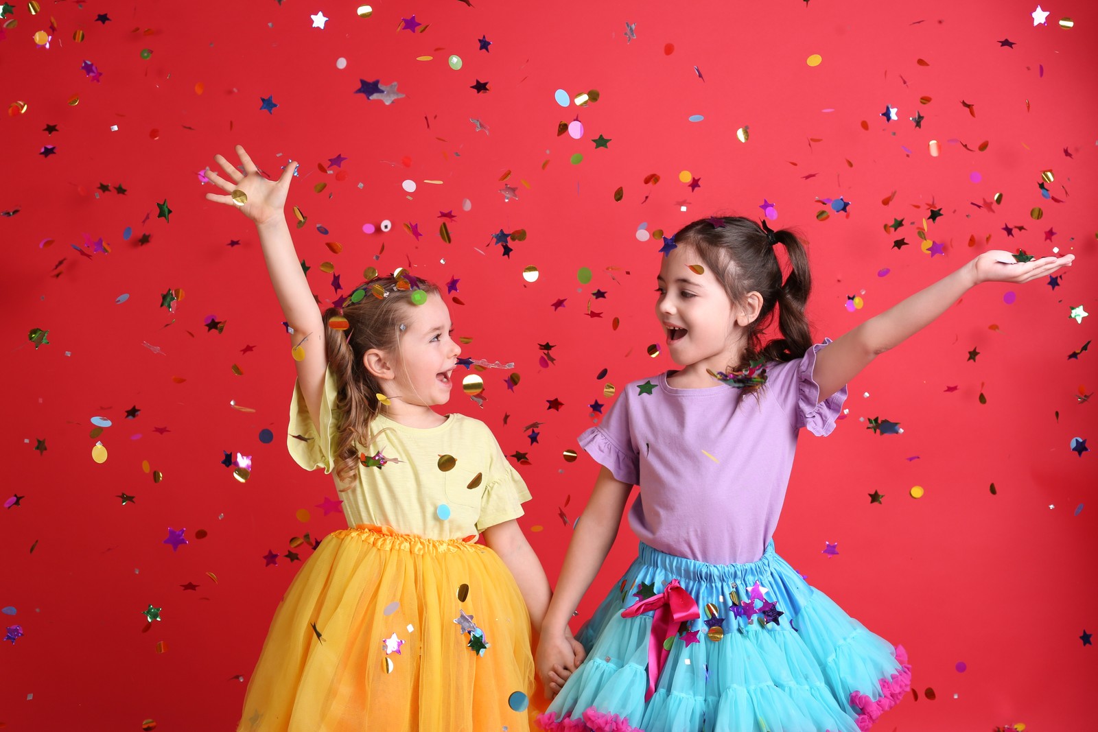 Photo of adorable little children and falling confetti on red background