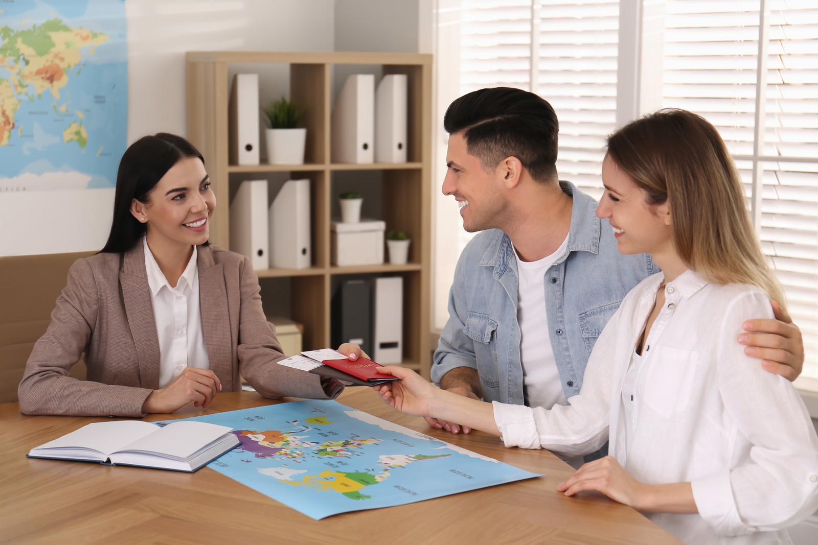 Photo of travel agent giving tickets and passports to clients in office