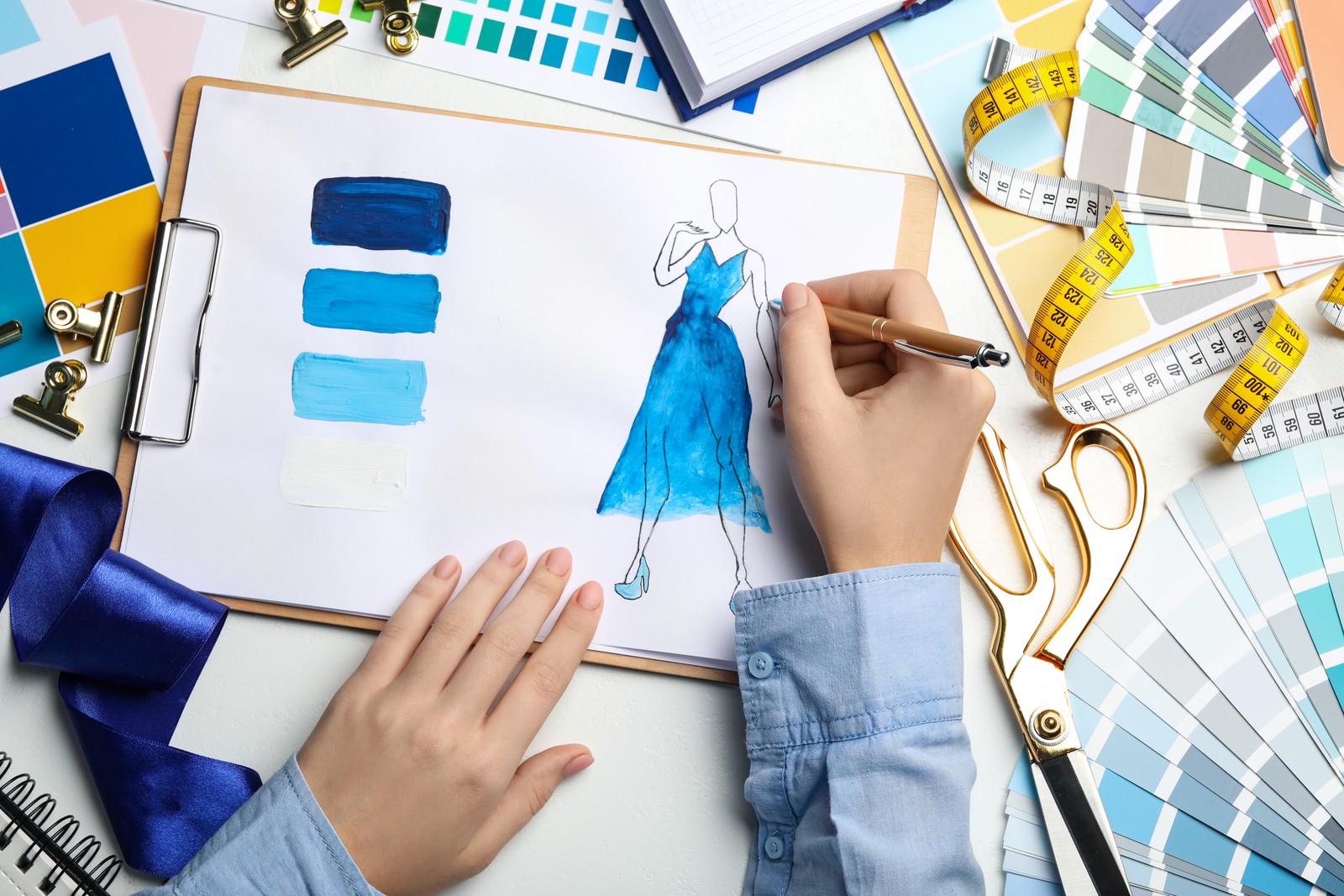 Photo of fashion designer drawing dress at table, top view