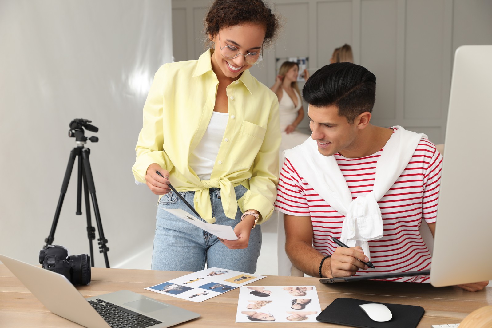 Photo of professional retoucher with colleague working at desk in photo studio