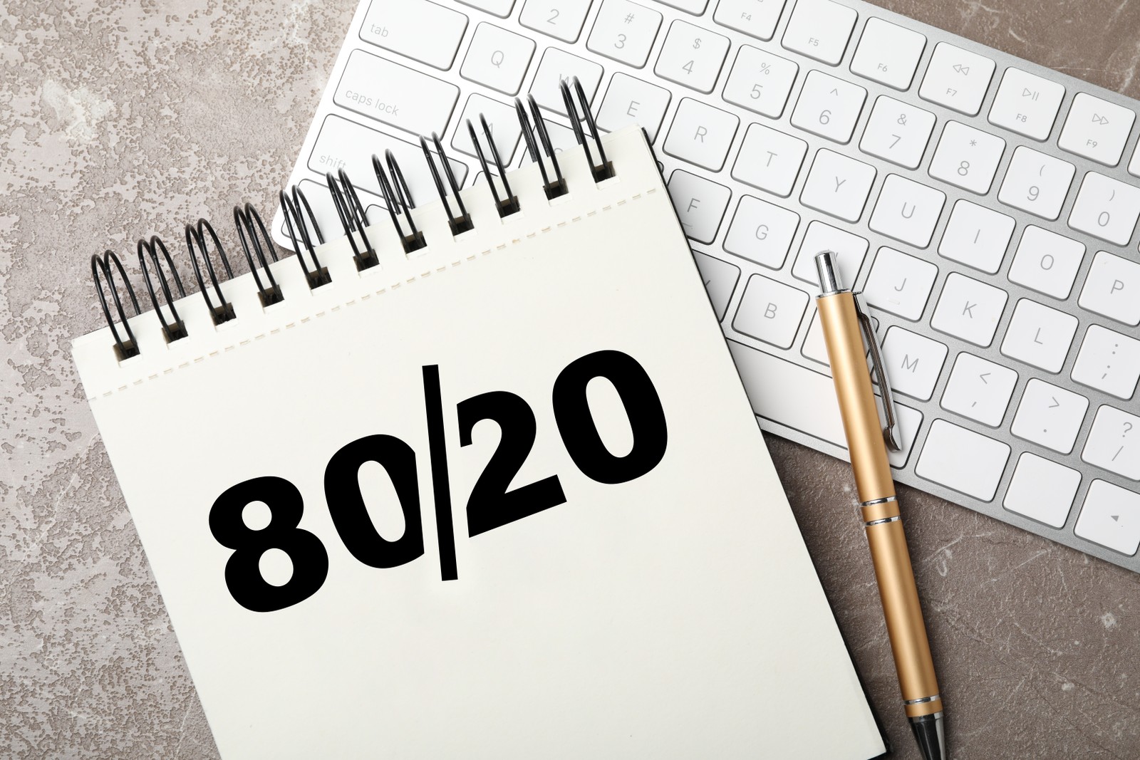 Photo of pareto principle concept. Notebook with 80/20 rule representation, pen and keyboard on grey background, flat lay