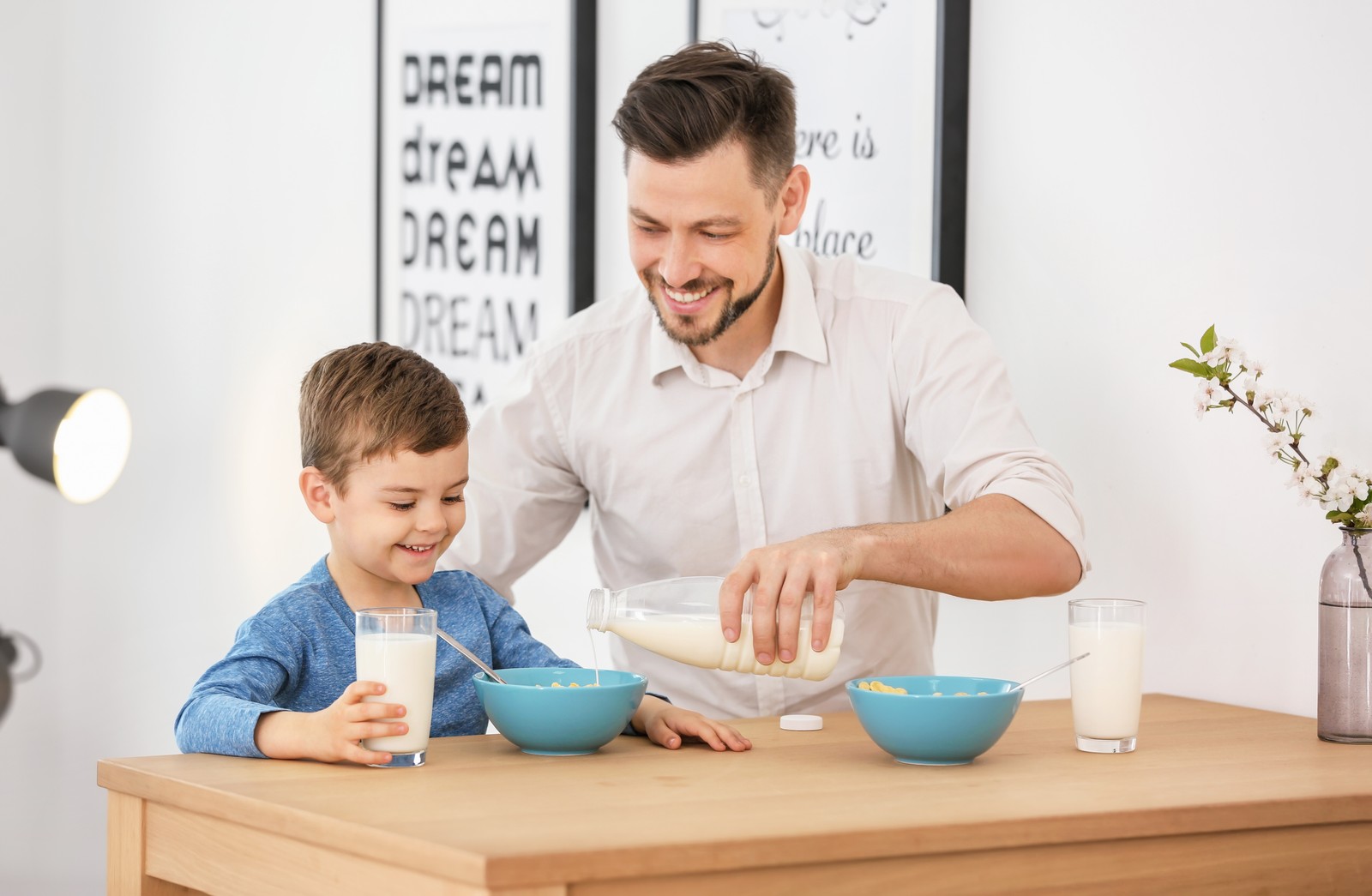 Photo of father and son having breakfast with milk at table