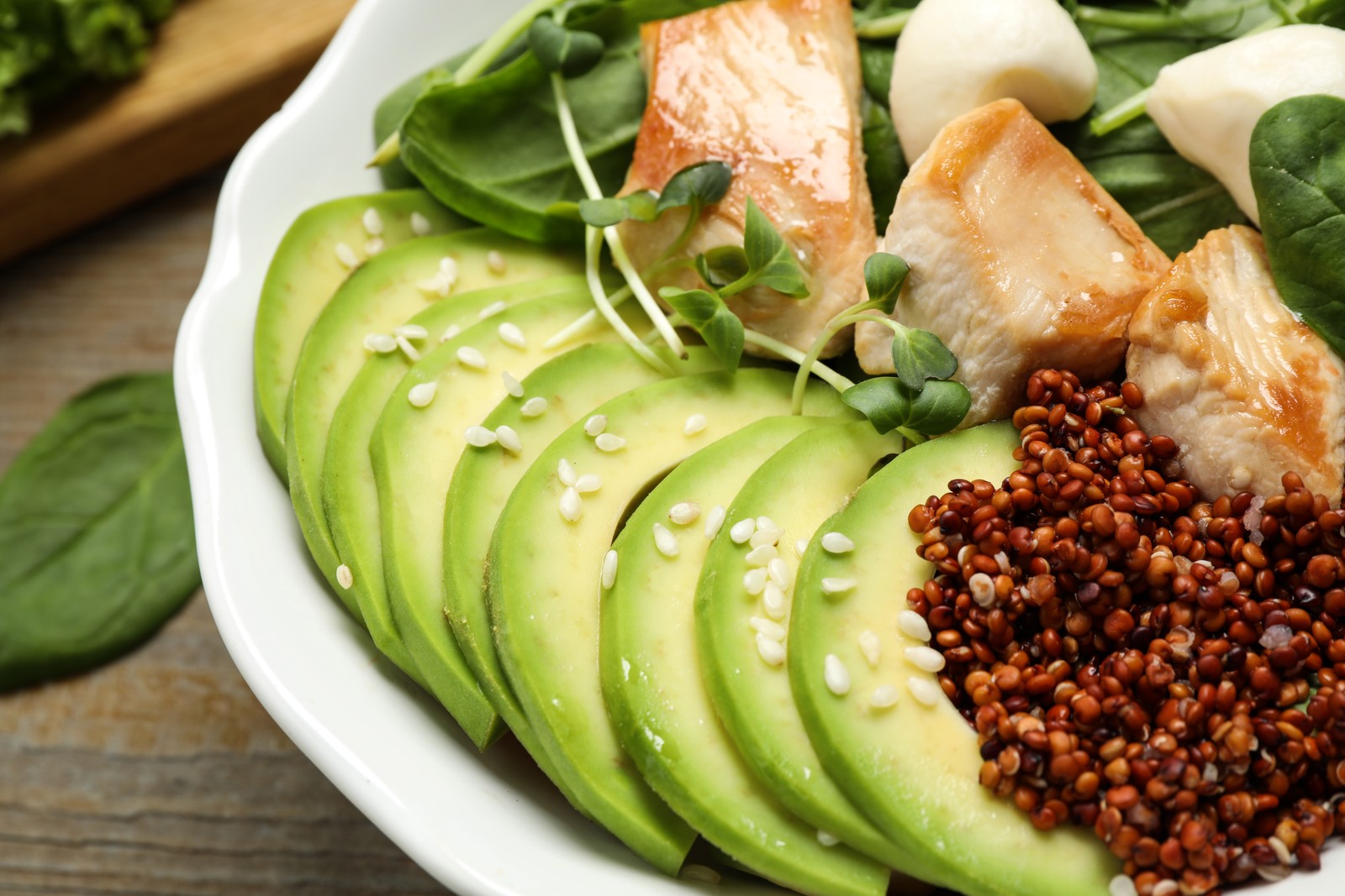 Photo of delicious avocado salad with chicken on wooden table, closeup