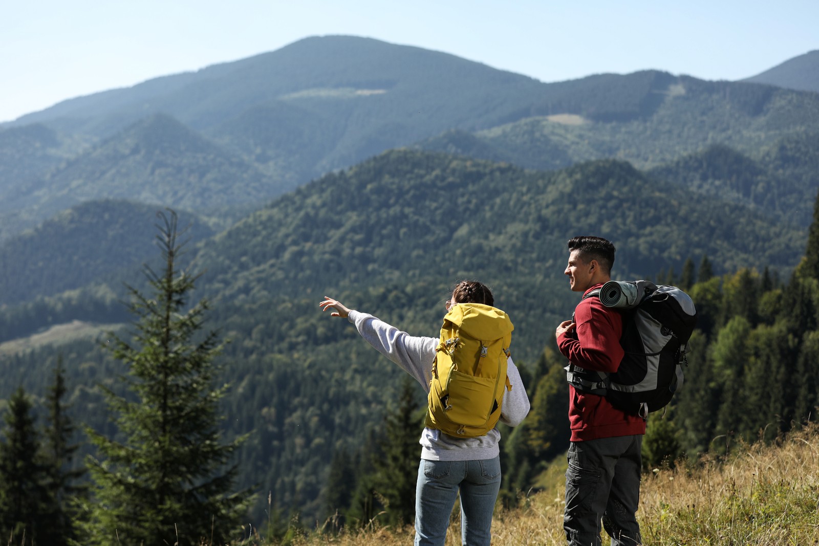 Photo of couple with backpacks enjoying mountain landscape on sunny day