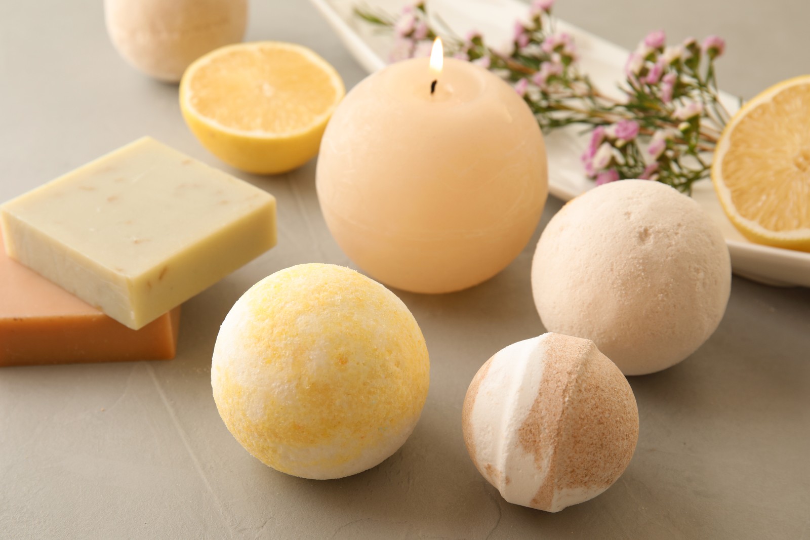 Photo of bath bombs, soap bars and scented candle on grey table