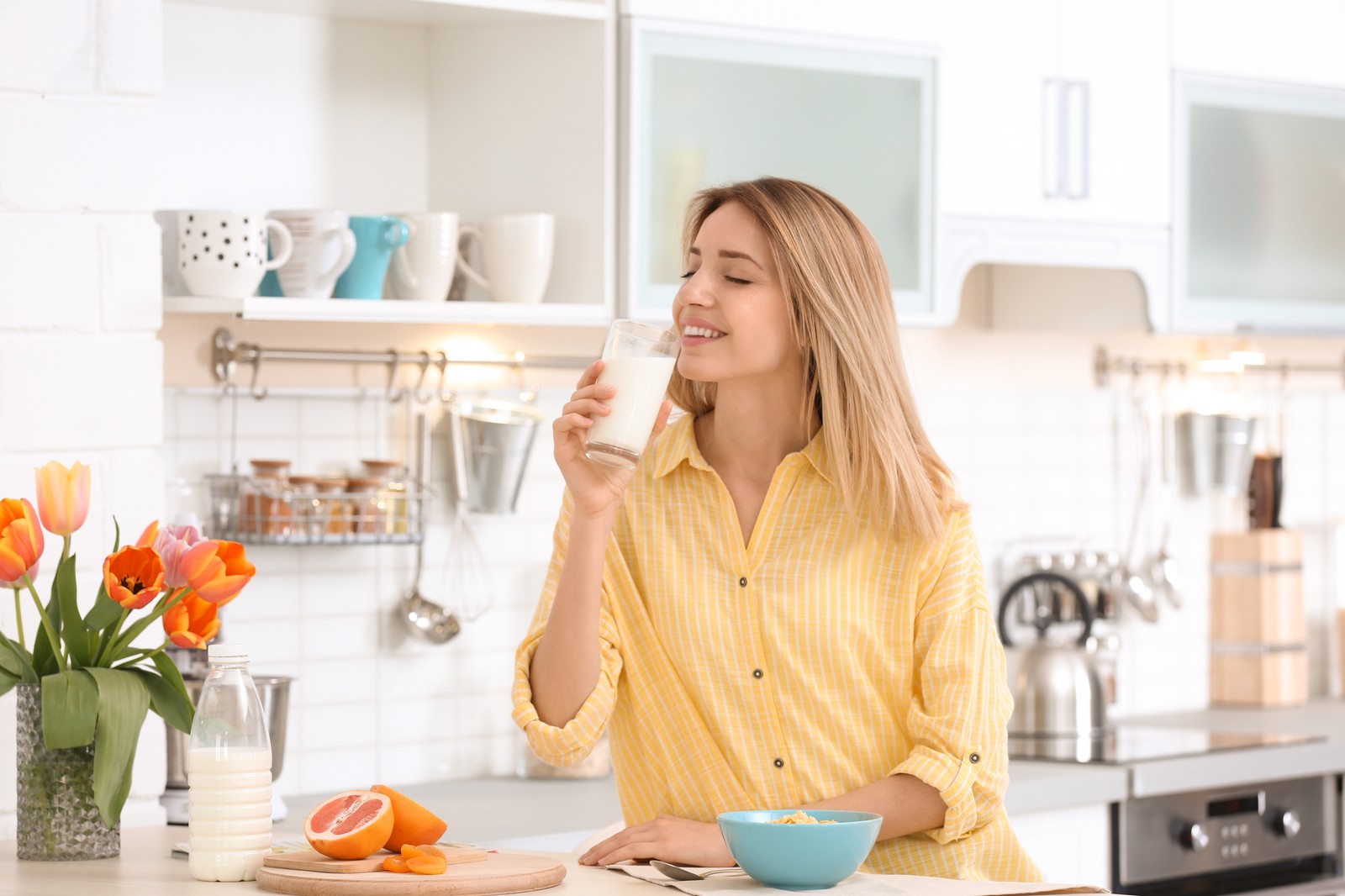 Photo of beautiful young woman drinking milk in kitchen