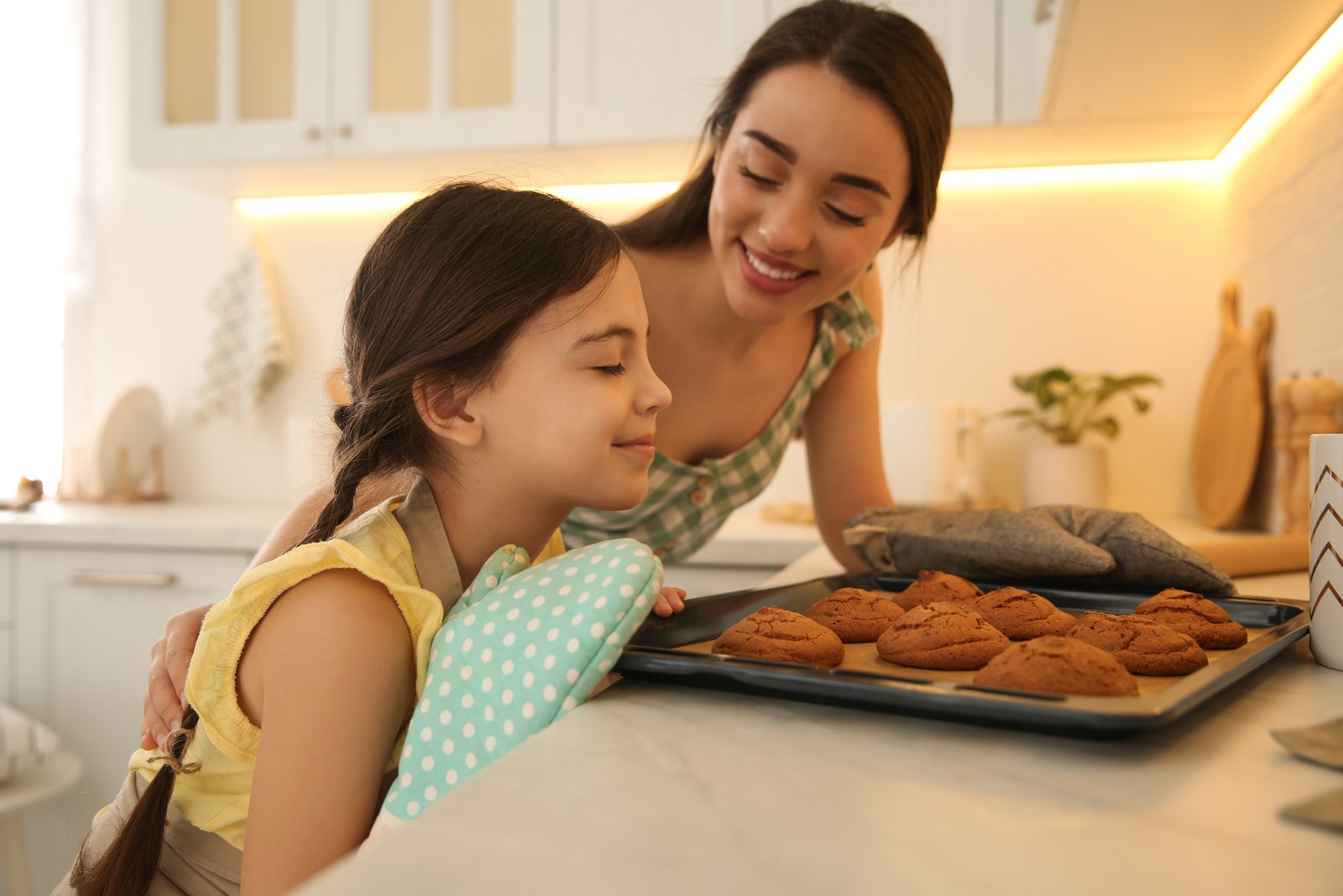 Photo of mother and daughter with freshly baked cookies in kitchen