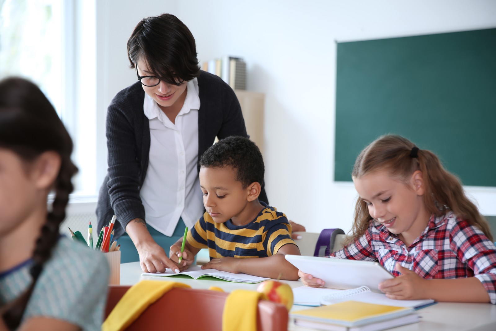 Photo of female teacher helping child with assignment at school