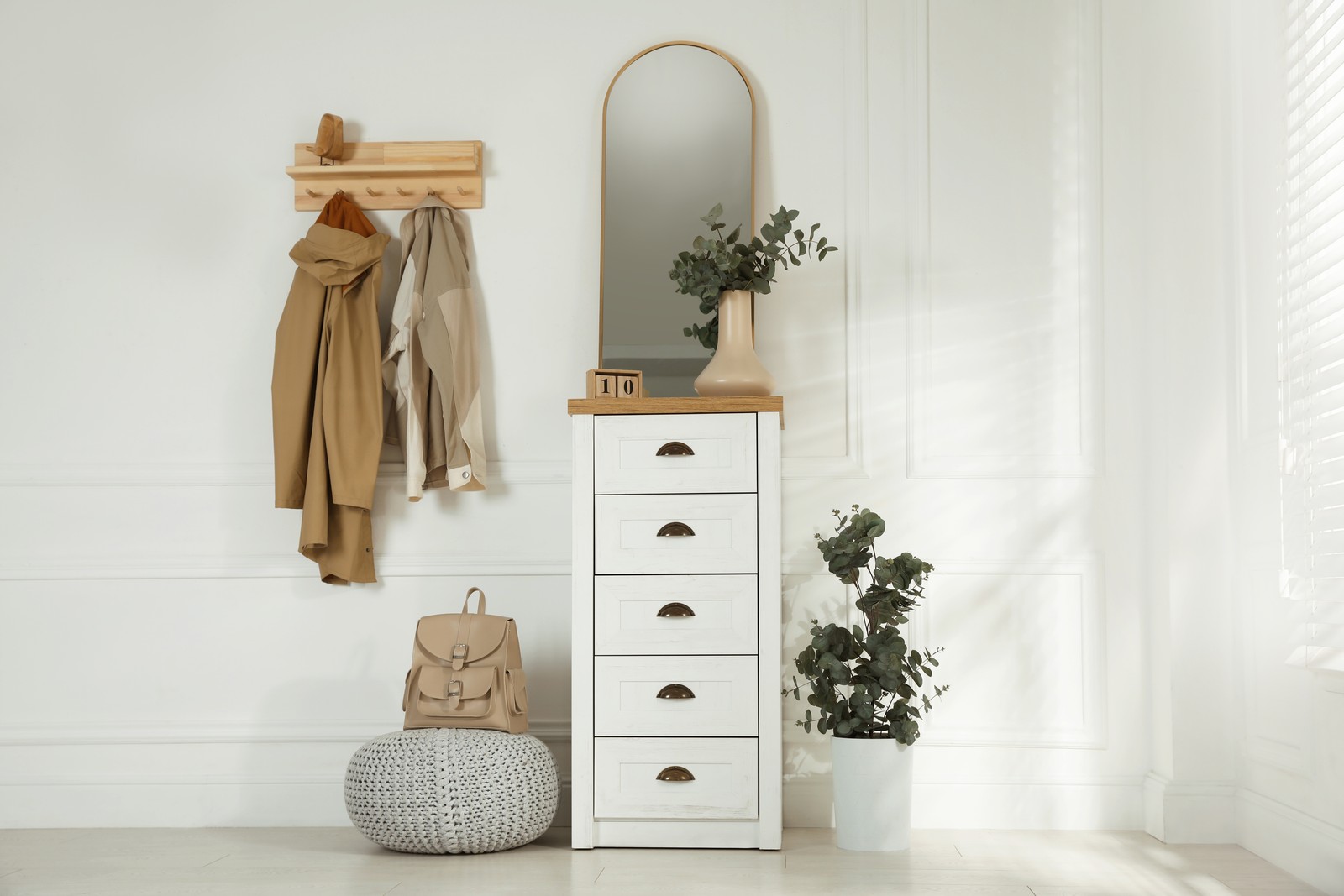 Photo of stylish hallway interior with coat rack, eucalyptus and mirror