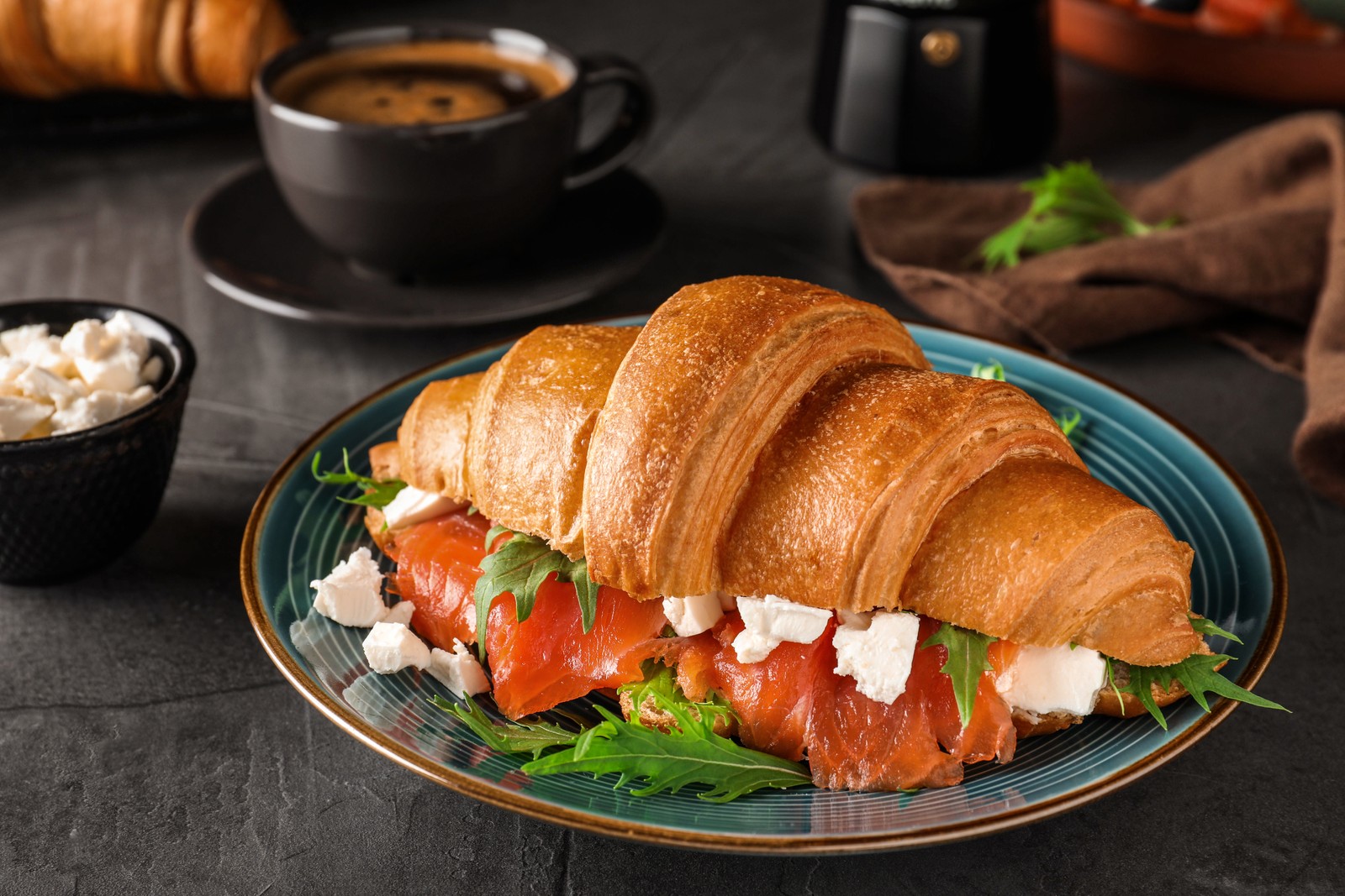 Photo of tasty croissant sandwich with red fish on grey table