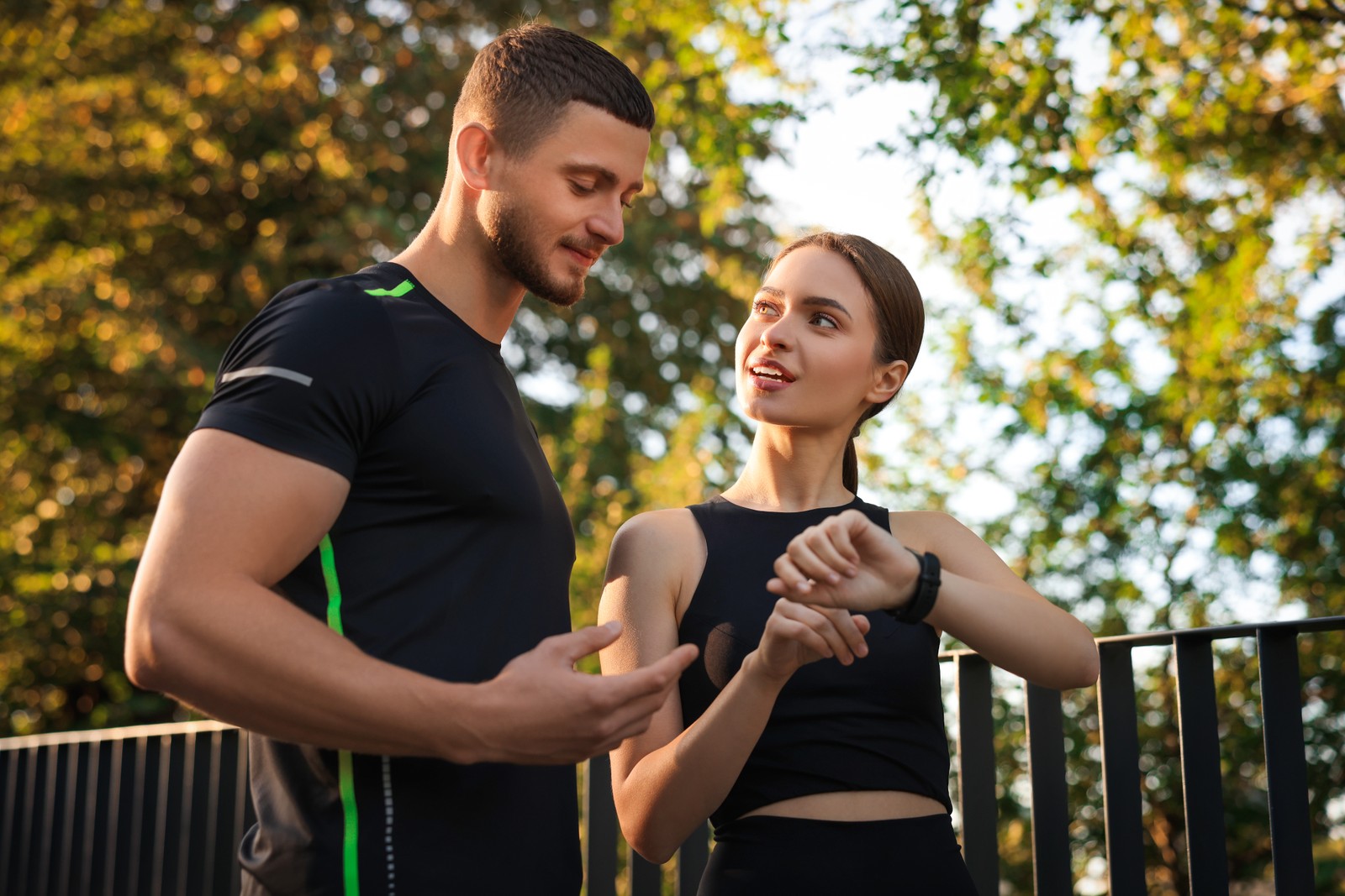 Photo of attractive couple checking pulse after training in park