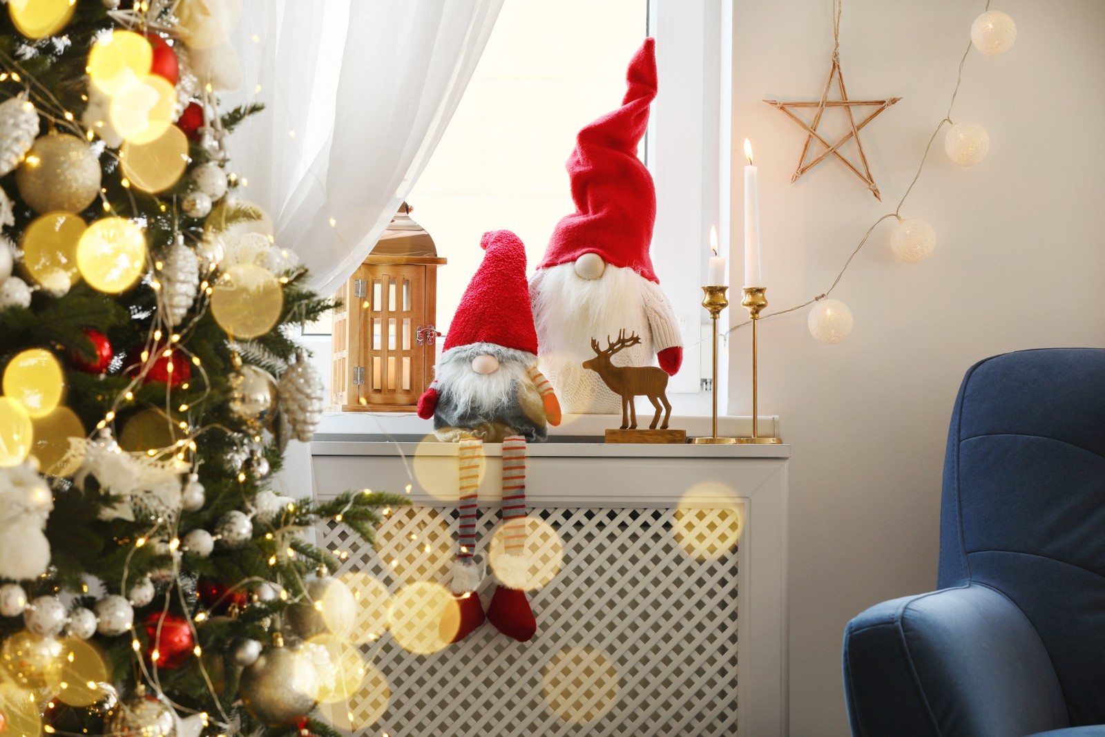 Photo of cute gnomes near Christmas tree on windowsill in room