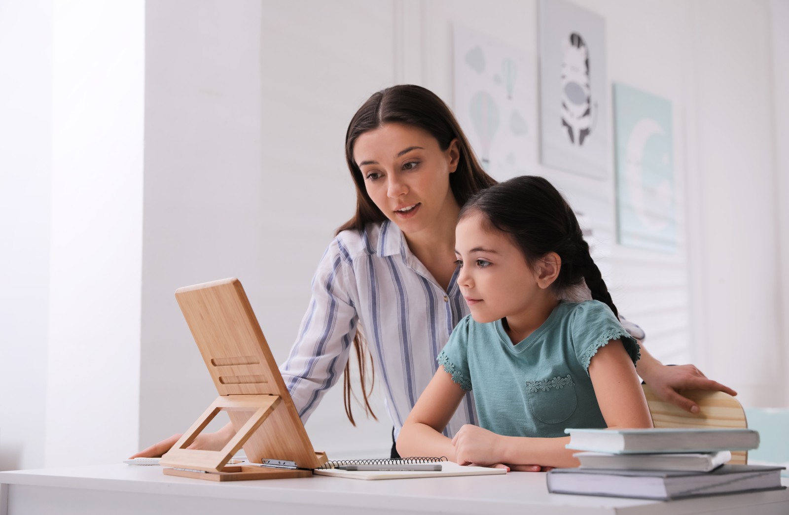 Photo of mother helping her daughter doing homework with tablet at home