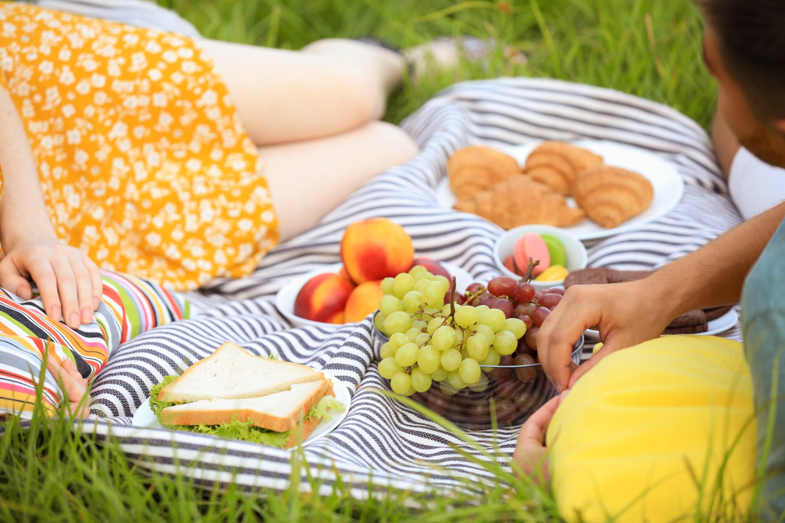 Photo of young couple having picnic on green grass, closeup