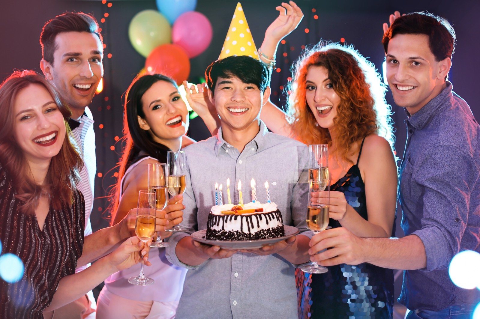 Photo of young people celebrating birthday with cake in nightclub