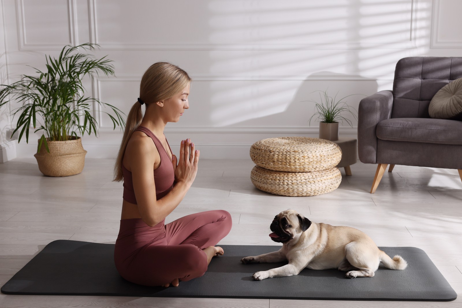 Photo of beautiful woman with dog practicing yoga at home