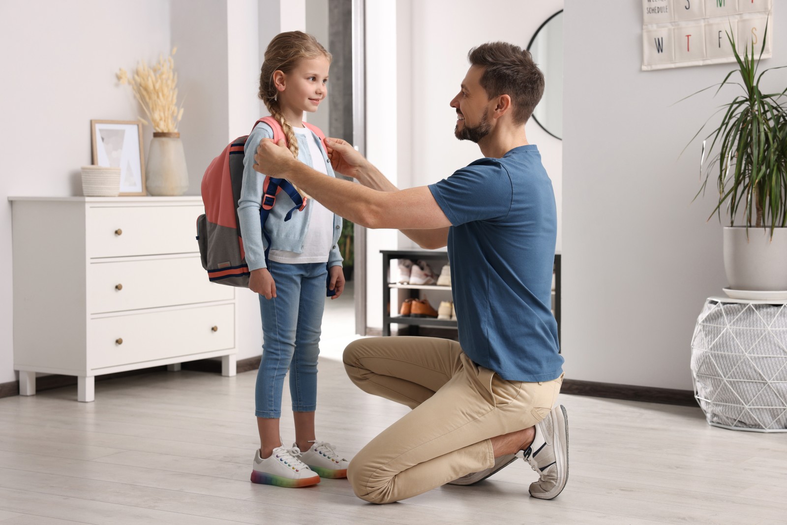 Photo of happy father preparing his daughter to school at home