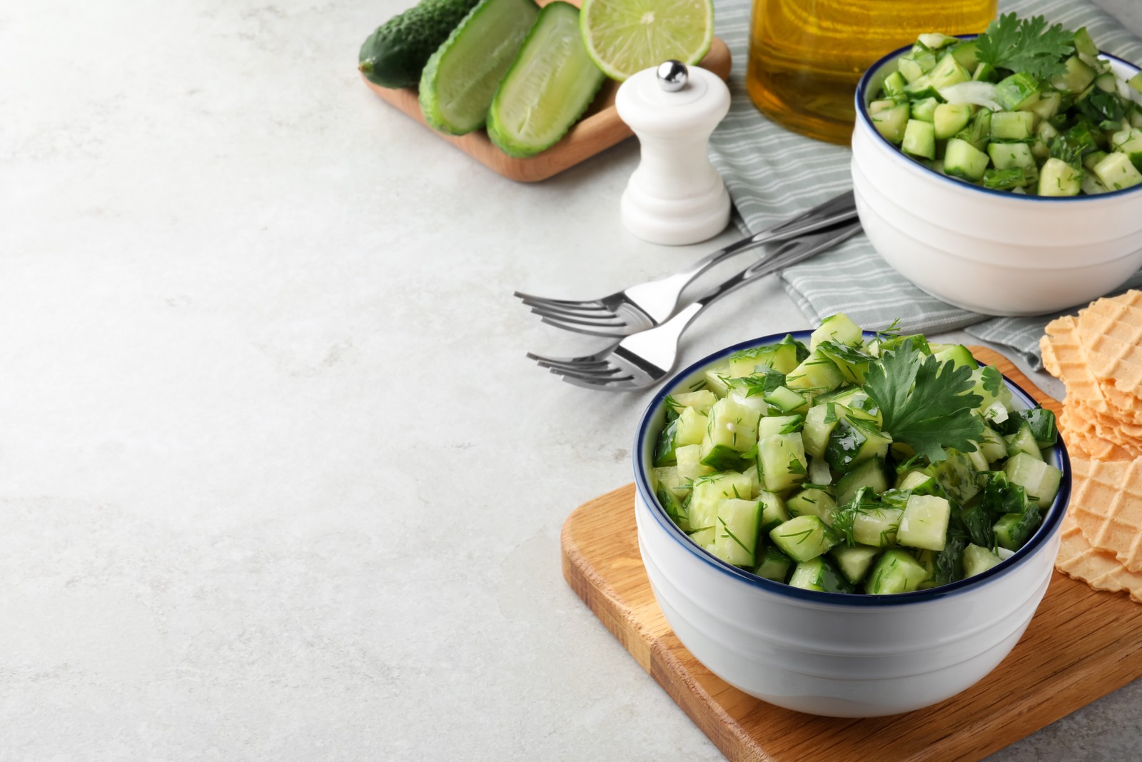 Photo of bowl of delicious cucumber salad served on light table. Space for text
