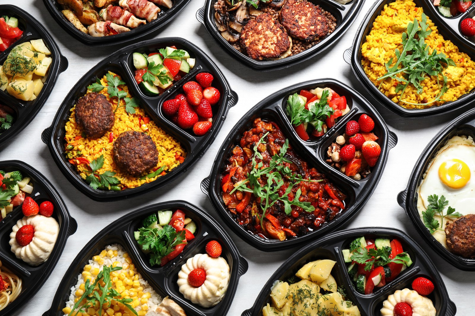 Photo of lunchboxes with different meals on white table, flat lay. Healthy food delivery