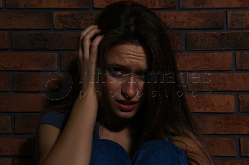 Abused young woman crying near brick wall. Domestic violence concept ...